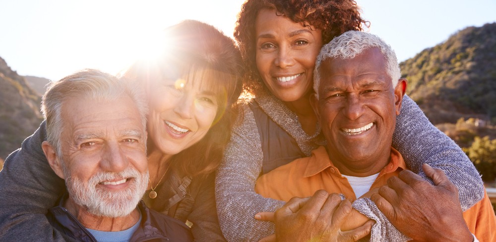 group of seniors smiling on a trail near a senior living community