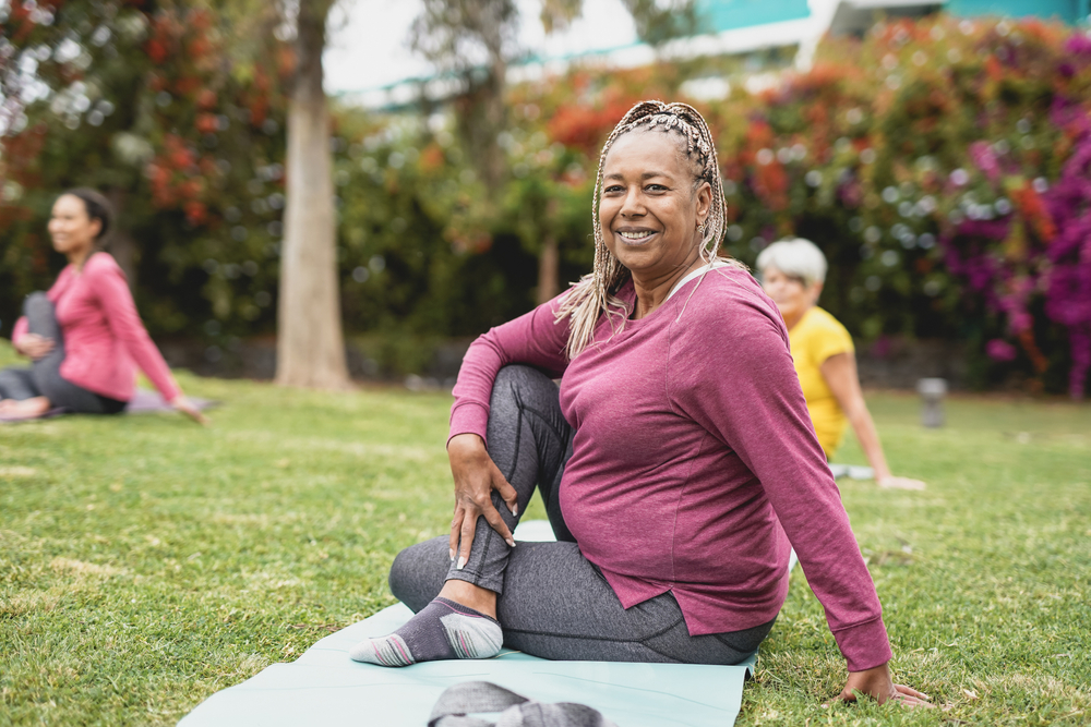 A senior woman practicing yoga outside in a group